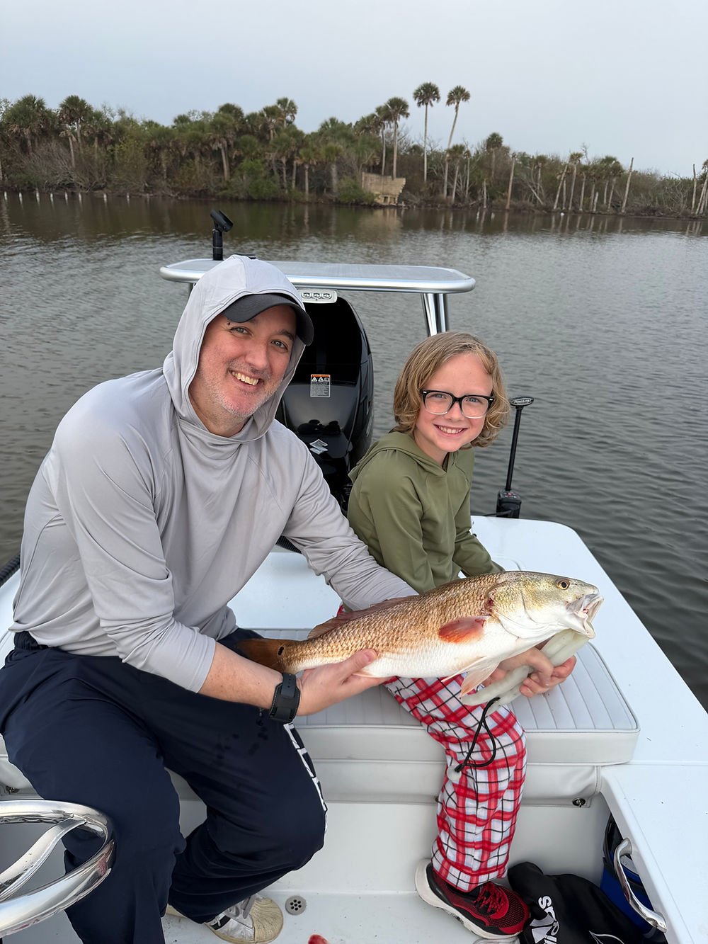 Father and son holding a redfish caught on a Line of Sight charter